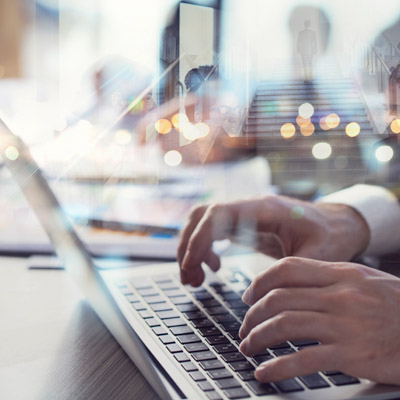 Typing on a laptop with data overlays, representing a stakeholder reviewing Oakford Group's market insights